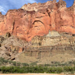 Des falaises colorées se montraient sur une plage de sable et une rivière.