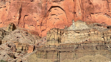 Des falaises colorées se montraient sur une plage de sable et une rivière.