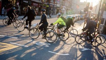 Cyclists and commuters make their ways home in evening sunshine at the junction of Fleet Street and Ludgate Hill in the City of London, aka the Square Mile - the capital