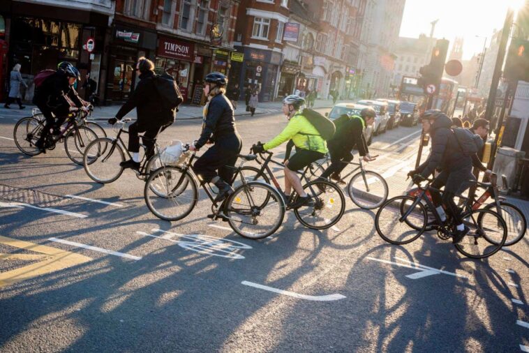 Cyclists and commuters make their ways home in evening sunshine at the junction of Fleet Street and Ludgate Hill in the City of London, aka the Square Mile - the capital