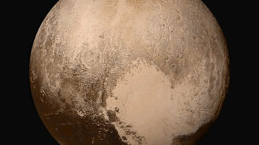 Une image haute résolution de Pluton. Une zone brillante et en forme de cœur domine le bas à droite, contrastant avec les plaines plus sombres et cratered et un terrain rugueux à travers le reste de la planète naine.