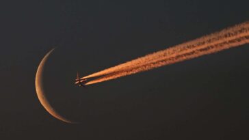 Crescent moon rise at dawn with passing passenger jet