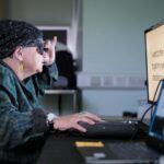 A study partipant wearing the glasses and testing her reading after being fit with the retinal implant