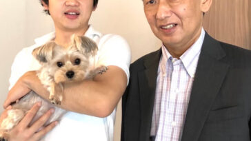 Photo d'un jeune homme tenant un chien debout à gauche d'un homme plus âgé