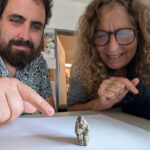 Une figurine en argile dévoile un changement de narration d'il y a 12 000 ans Un homme montre une petite figurine en argile posée sur une feuille de papier blanc sous le regard d’une femme.