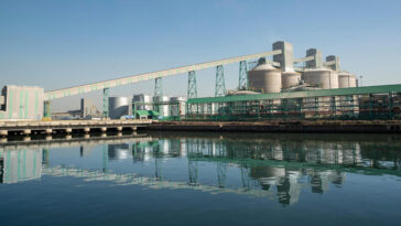 Une fonderie d'aluminium au Mozambique se reflète dans l'eau calme au premier plan.