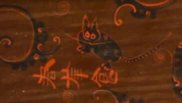 Un dessin sur un artefact comprend un dessin de ce qui ressemble à un chat noir avec des oreilles pointues et pelucheuses, des griffes pointues, des taches sur le dos et des rayures sur la queue.