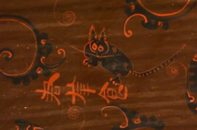 Un dessin sur un artefact comprend un dessin de ce qui ressemble à un chat noir avec des oreilles pointues et pelucheuses, des griffes pointues, des taches sur le dos et des rayures sur la queue.