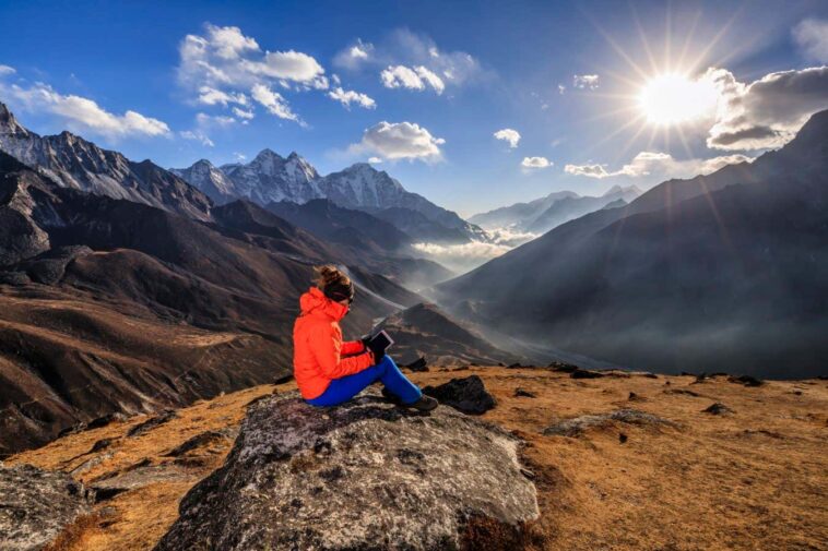Young woman, wearing a orange jacket, is reading a book on an ebook reader during sunset over Himalayas. She is sitting on the top of a mountain and holding the e-reader.The afternoon sun on the background. Mount Everest National Park. This is the highest national park in the world, with the entire park located above 3,000 m ( 9,700 ft). This park includes three peaks higher than 8,000 m, including Mt Everest. Therefore, most of the park area is very rugged and steep, with its terrain cut by deep rivers and glaciers. Unlike other parks in the plain areas, this park can be divided into four climate zones because of the rising altitude. The climatic zones include a forested lower zone, a zone of alpine scrub, the upper alpine zone which includes upper limit of vegetation growth, and the Arctic zone where no plants can grow.