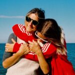 Woman hugging her mother in front of sea under sky