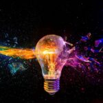 2WKKMAM Vivid image of a light bulb shattering with a dynamic multicolored glass fragment splash