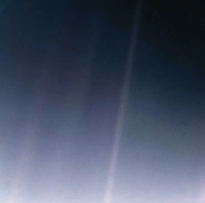 Un faible faisceau de lumière traverse un ciel sombre, avec un petit point lumineux près de son centre.