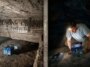 Un chercheur à l'intérieur d'une chambre sombre de la Grande Pyramide d'Égypte porte une lampe frontale et regarde une boîte bleue, avec une deuxième boîte grise à proximité - un équipement utilisé pour mesurer les vibrations à l'intérieur de la pyramide.