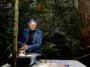 Un chercheur travaillant sur un instrument assis sur une table dans une forêt tropicale.