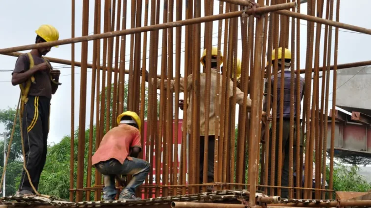 Workers place reinforcement bars for a pier of the Parama–Park Circus flyover under construction in Kolkata, 31 July 2012. (Photo by Biswarup Ganguly), CC BY 3.0, modified, https://commons.wikimedia.org/wiki/File:Piller_Rebar_Placement_-_Parama-Park_Circus_Flyover_Construction_-_Kolkata_2012-07-31_0553.JPG