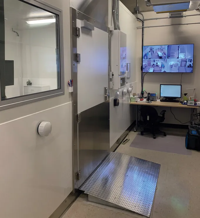 Dans le laboratoire de l'Unité de recherche en physiologie humaine et environnementale de l'Université d'Ottawa. Le mur de gauche a une porte et une fenêtre donnant sur la pièce voisine. Le long du mur du fond se trouve un bureau avec un écran d’ordinateur et, au-dessus, un écran plus grand affichant les images en direct de quatre caméras.