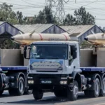 Kheibar Shekan missiles on trucks at the Sacred Defence Week armed forces parade, Tehran, September 22, 2023 (Photo by Mohammad Hossein Ghanbarian / SNN), Attribution licence, modified, https://commons.wikimedia.org/wiki/File:Kheibar_Shekan_missiles_Sacred_Defence_Week_parade_2023.jpg