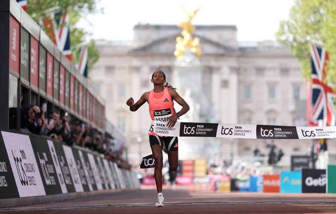Une femme traverse la bande à la ligne d'arrivée du marathon de Londres du TCS.